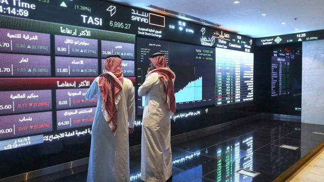 Two investors monitor stock prices on the Saudi Tadawul screen